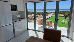 Une cuisine moderne dotée d’une grande porte-fenêtre coulissante qui donne sur une terrasse offrant une vue sur l’océan.