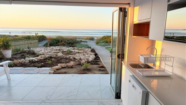 Une cuisine moderne avec vue sur la plage, un chemin en pierre et un petit jardin.