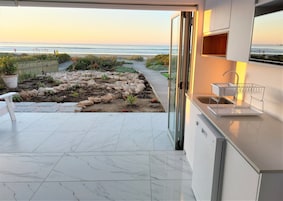 Una cocina moderna con vistas a la playa, un sendero de piedra y un pequeño jardín.