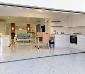 A modern kitchen with white cabinets, a stove, and a dining area with a table and chairs.
