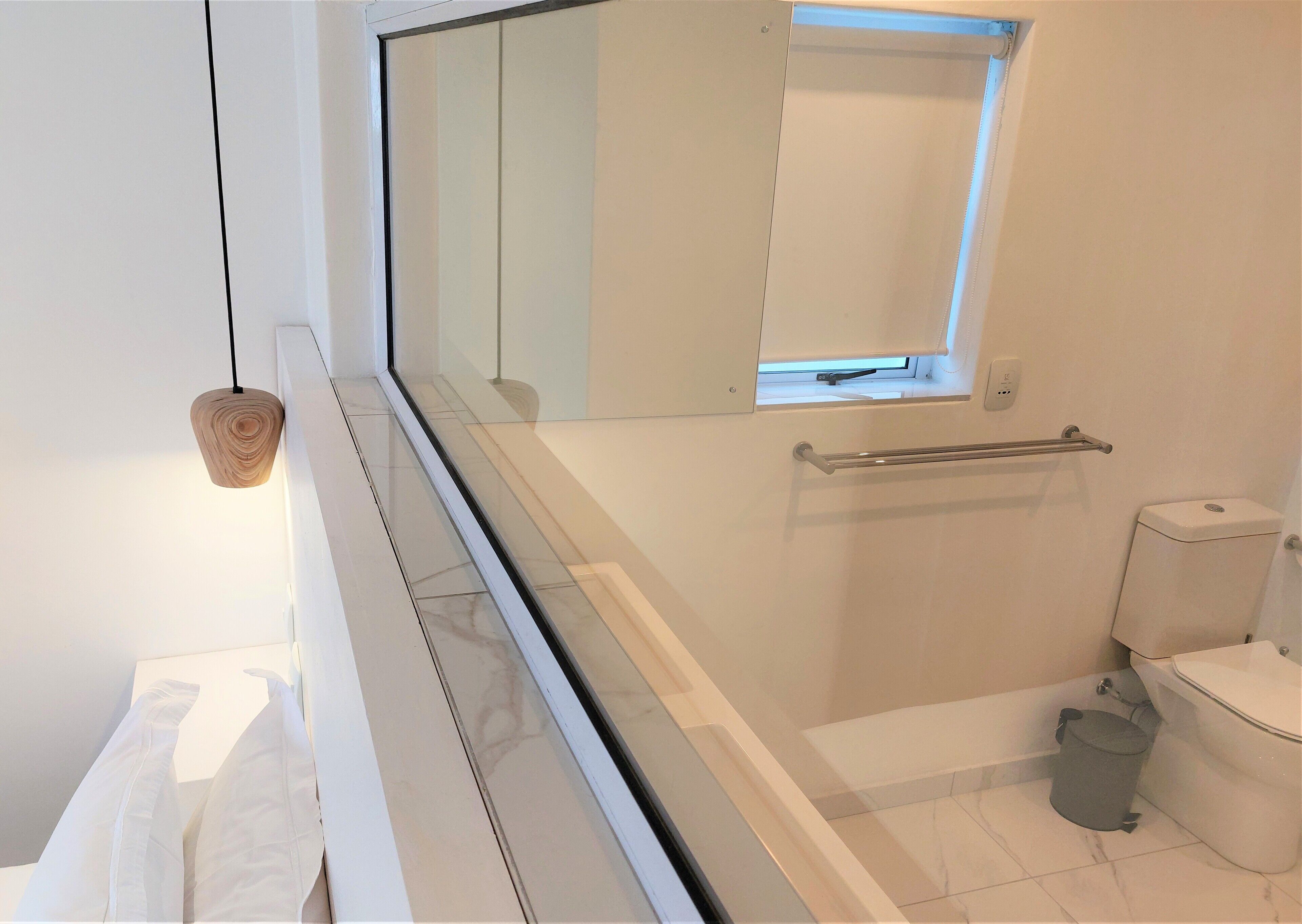 Un baño moderno con cabina de ducha de vidrio, inodoro y un ventanal.