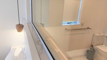 Un baño moderno con cabina de ducha de vidrio, inodoro y un ventanal.