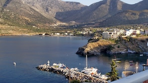 A coastal town with a marina, rocky shoreline, and mountainous backdrop.