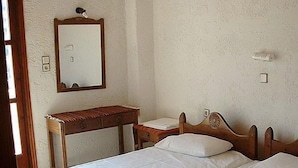 A bedroom with a wooden bed, a nightstand, a mirror, and a wall-mounted light fixture.