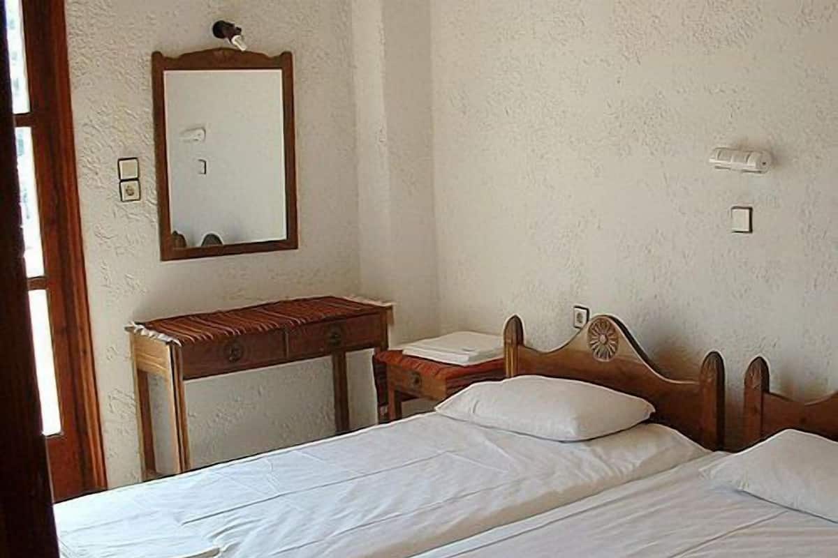 Une chambre à coucher avec un lit en bois, une table de chevet, un miroir et un luminaire fixé au mur.