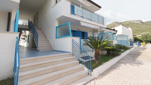 Un bâtiment à deux étages, doté d’un escalier, d’un balcon et offrant une vue sur une colline.