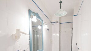 Une salle de bain équipée d’un lavabo, d’un miroir, de toilettes, d’une douche et d’un lave-linge.