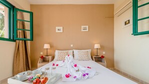 A hotel room with a bed, two bedside lamps, a tray with breakfast items, and a window with curtains. - Alpha Stegna Sun (Rhodes)