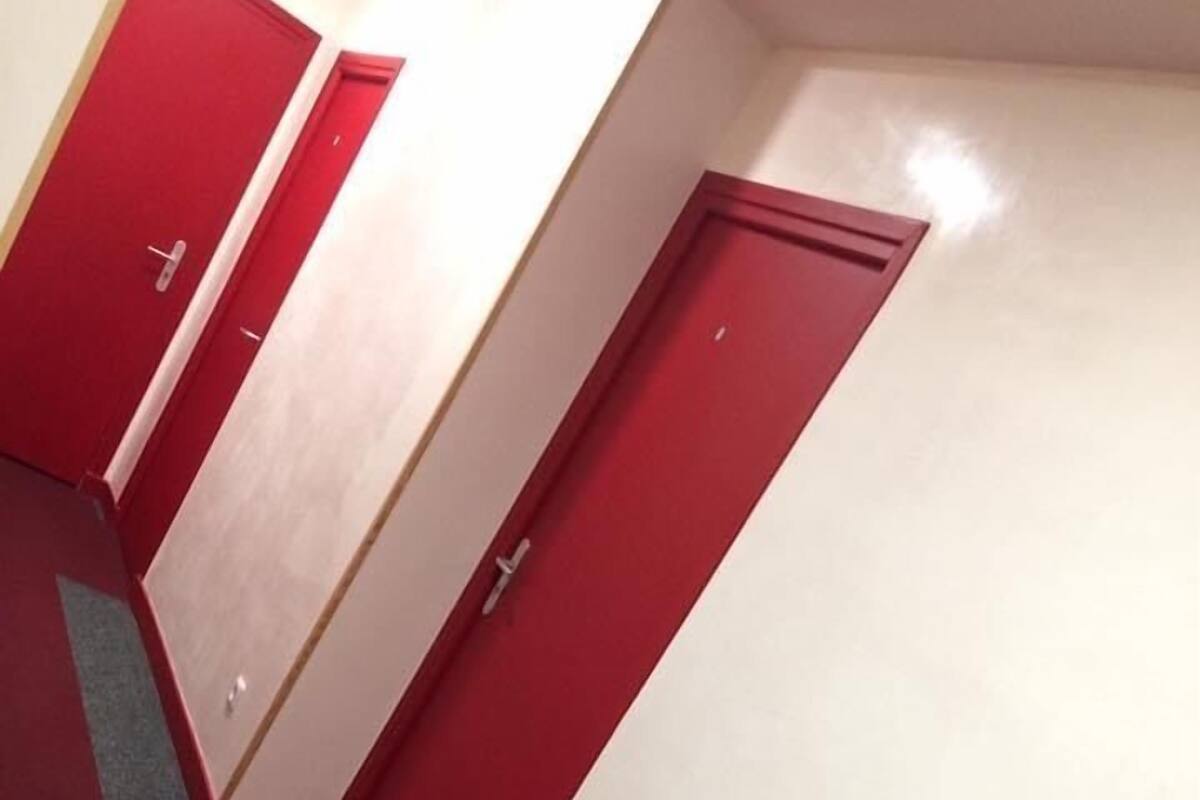A corridor with red doors and a carpeted floor.