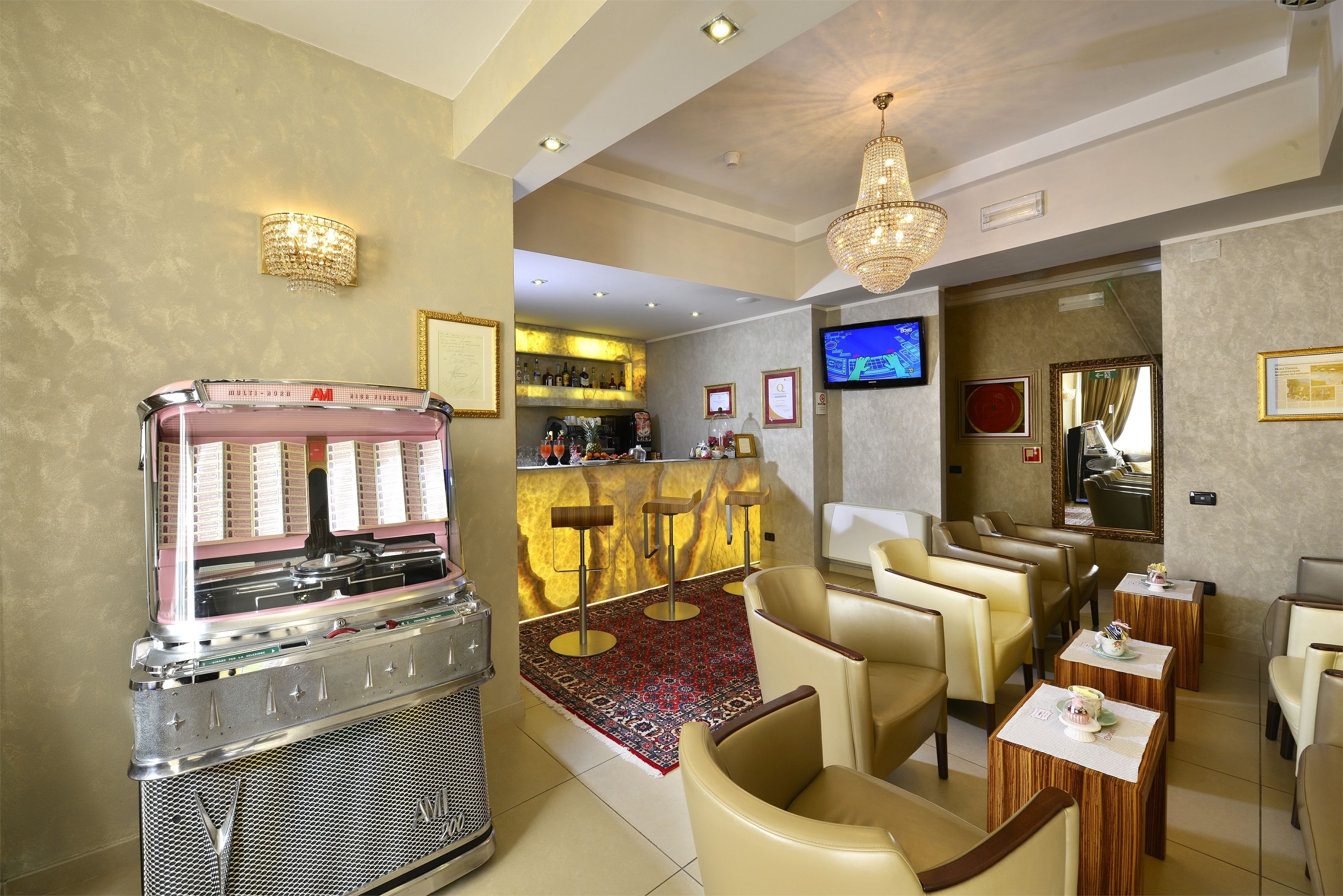 Un hall d’hôtel doté d’un juke-box, d’un bar, de sièges confortables et d’un téléviseur.