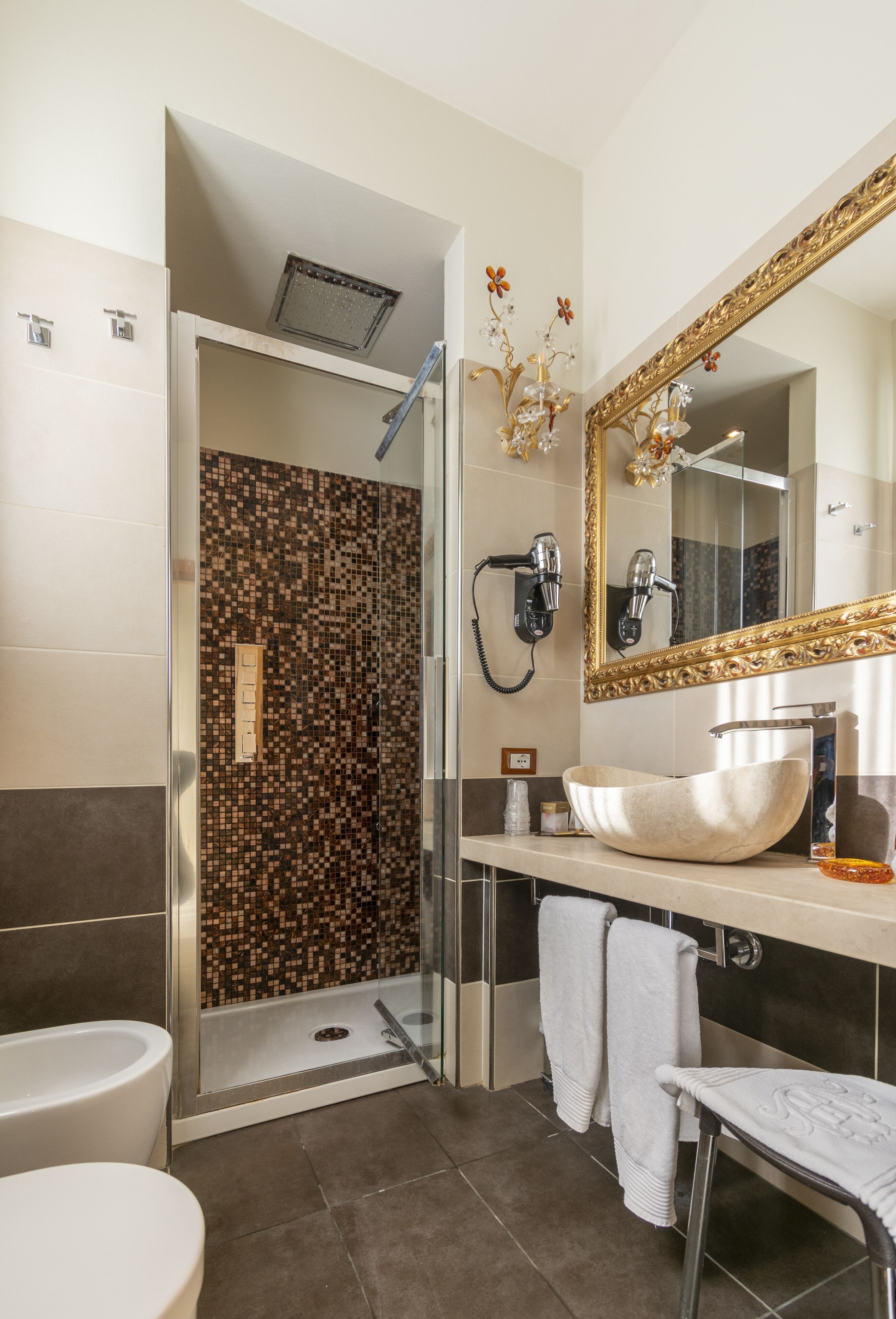 Un baño moderno con ducha de vidrio, un espejo grande y un lavamanos blanco.