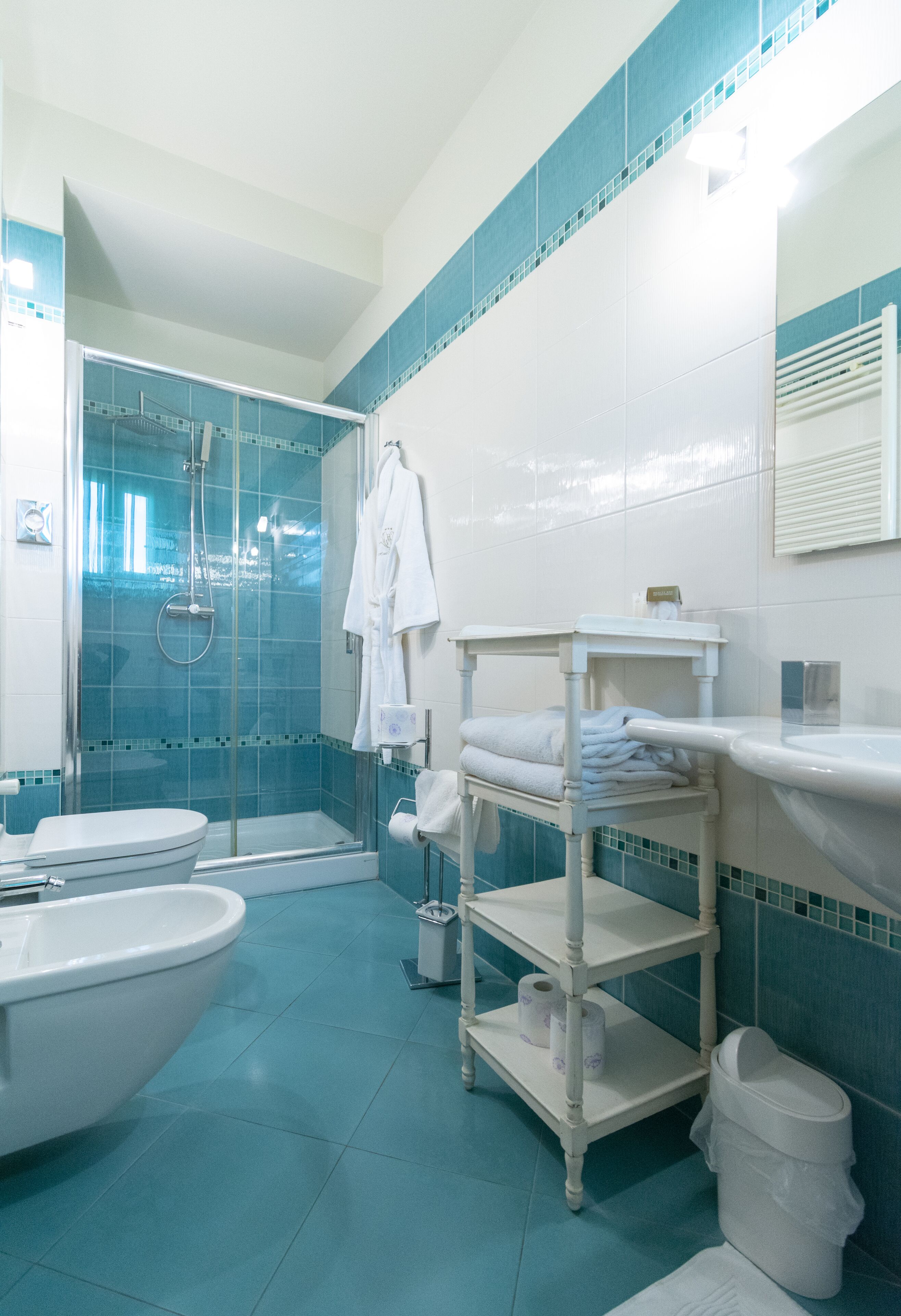 A bathroom with a glass-enclosed shower, a white sink, and a vanity with a mirror.