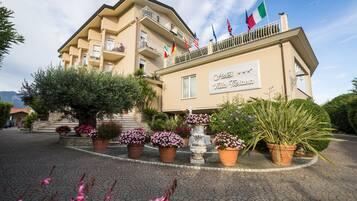 A hotel with multiple balconies, a sign reading "Hotel Villa Tiana," and flags of various countries.