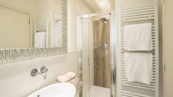 A modern bathroom with a glass-enclosed shower, a white sink, and a towel rack with multiple towels.