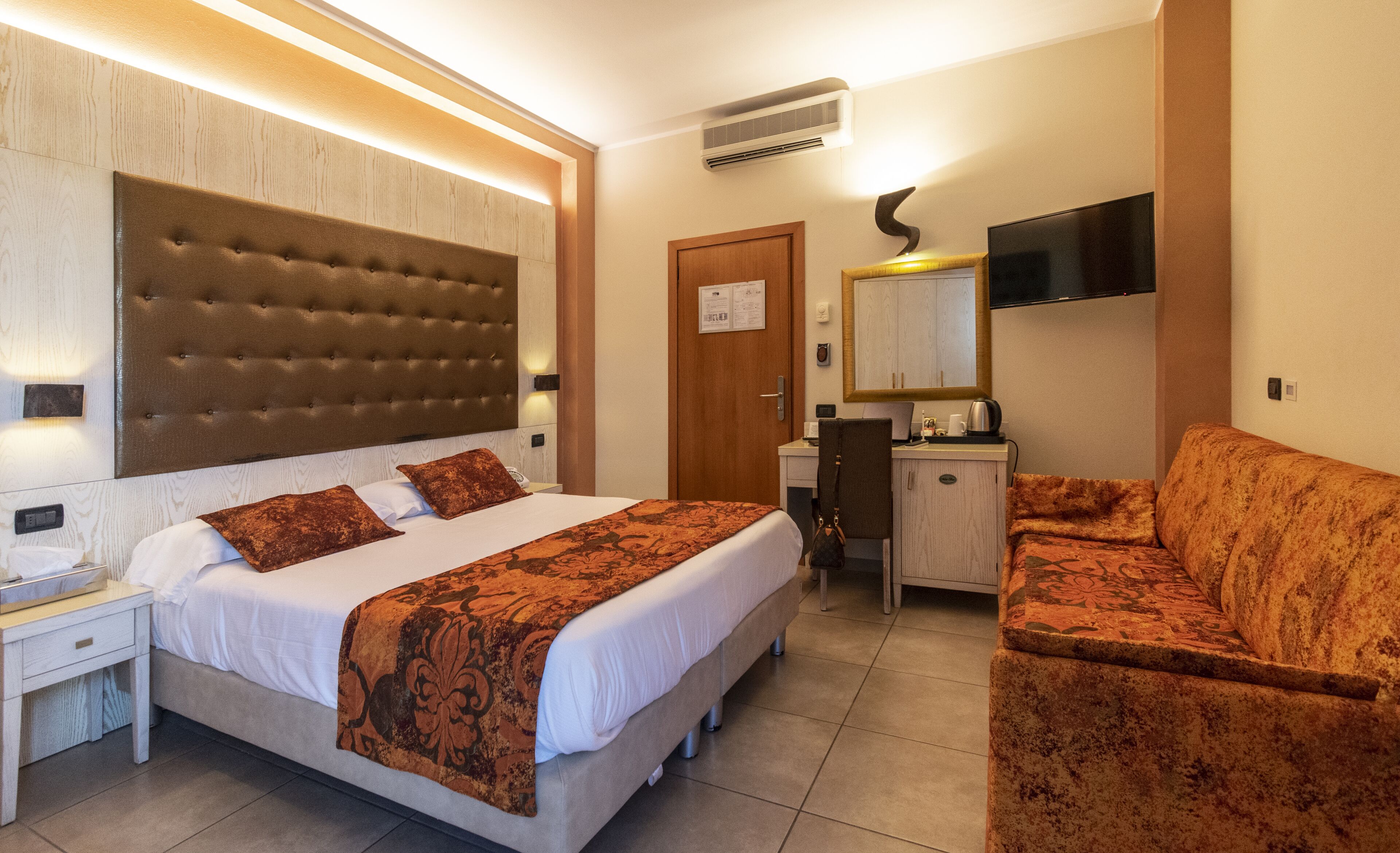 A hotel room with a large bed, a desk, a chair, and a television.