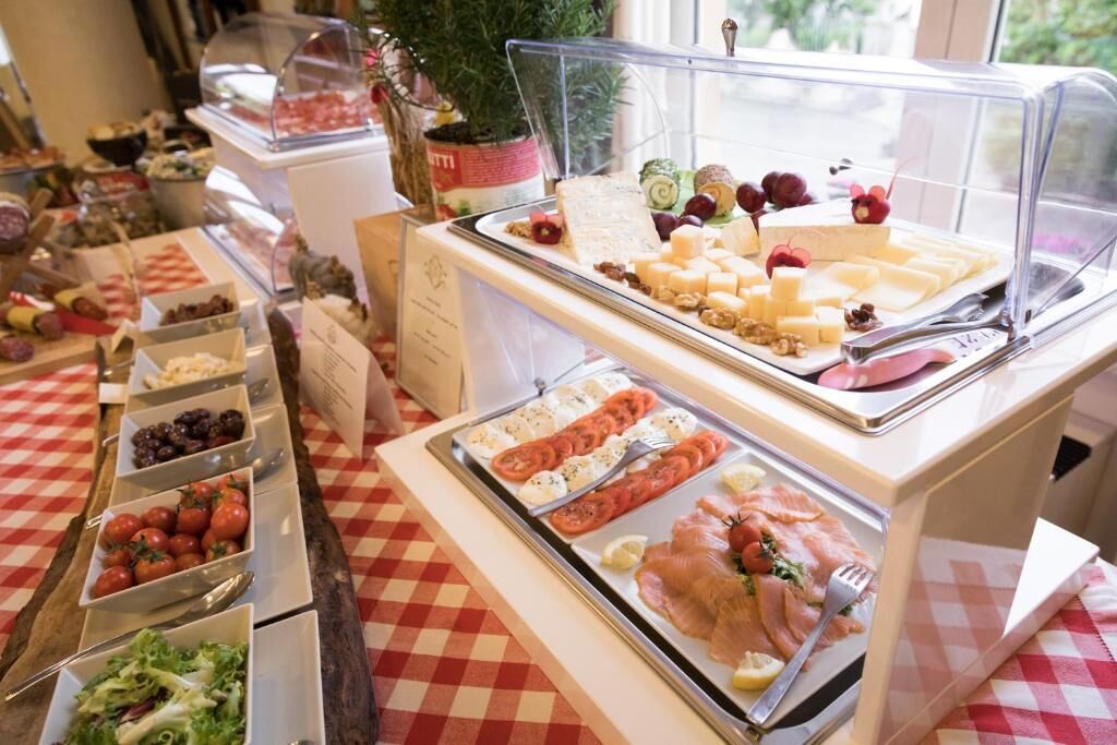 Un bufé con diversas opciones de comida, incluyendo quesos, carnes y ensaladas.