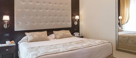 A modern hotel room with a large bed, a wall-mounted air conditioner, and a large mirror.