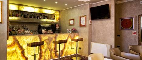 A bar area with a marble countertop, bar stools, and a television mounted on the wall.
