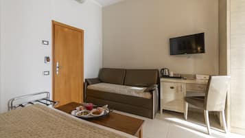 Una habitación de hotel con cama, sofá, escritorio, silla y televisor.