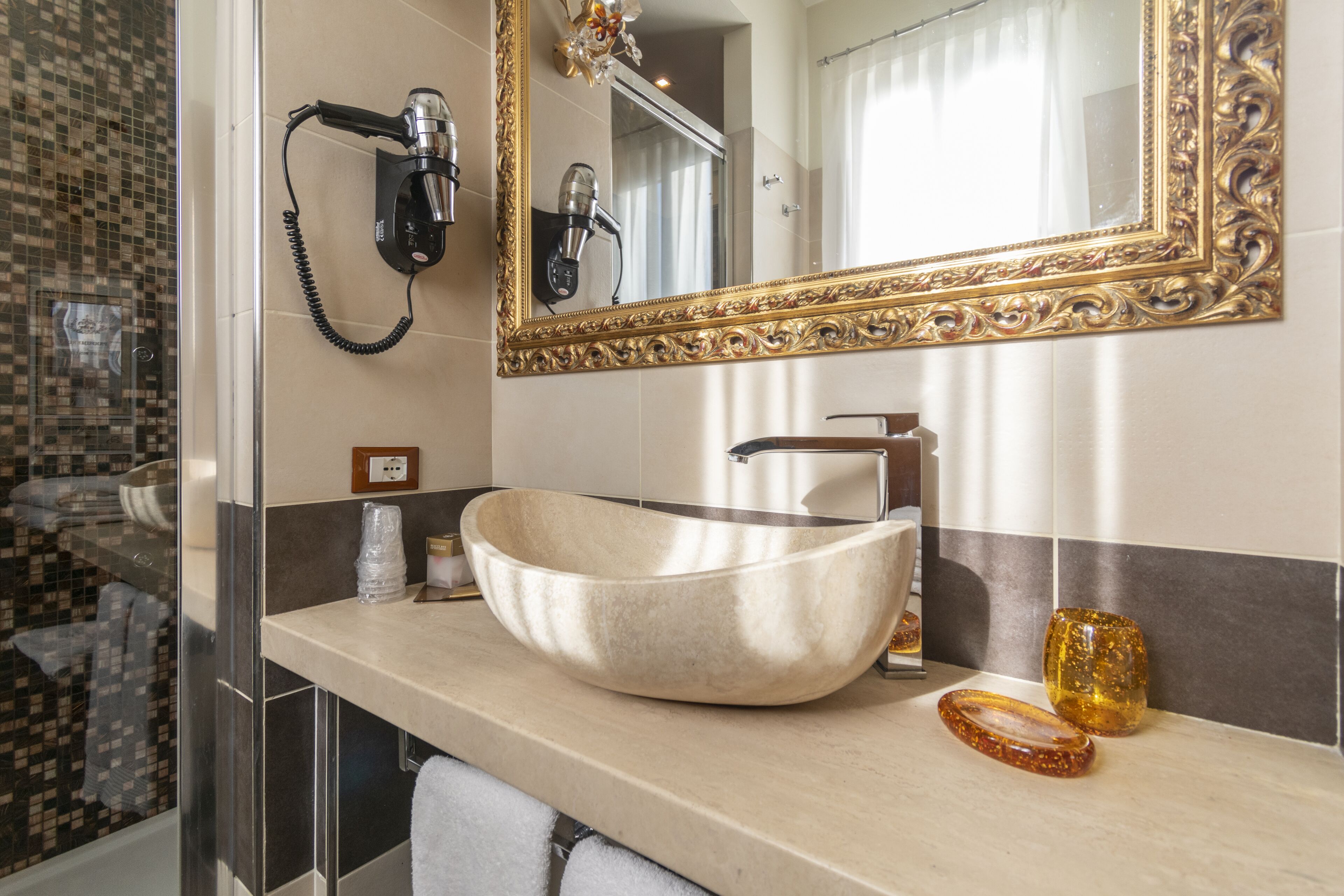 A bathroom with a large mirror, a sink, and a hairdryer mounted on the wall.