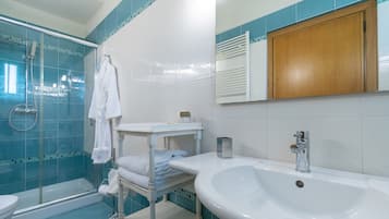 Ein Badezimmer mit einer gläsernen Duschkabine, einem weißen Waschbecken und einem Holzschrank.
