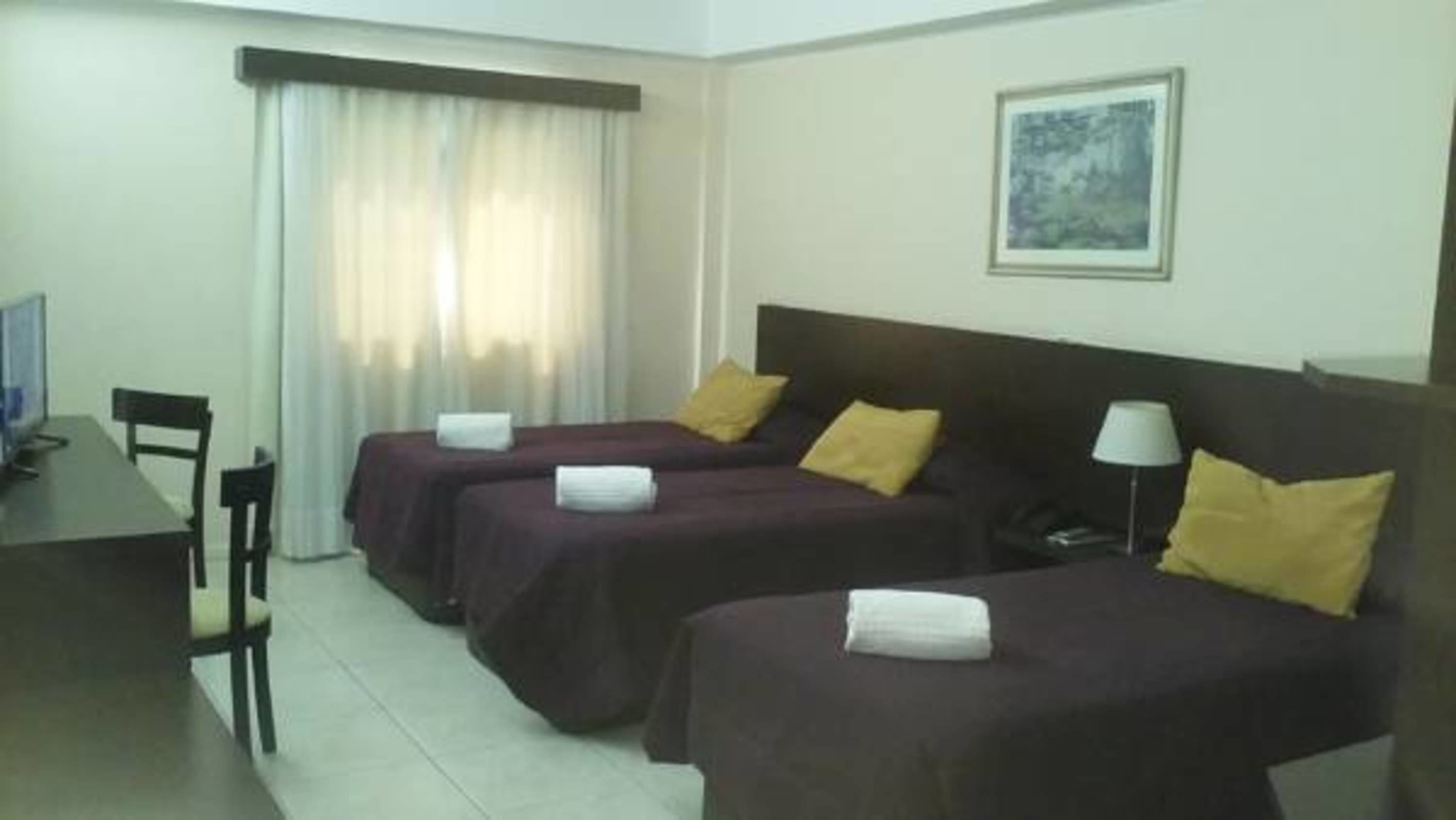 A hotel room with two beds, a desk, and a chair.