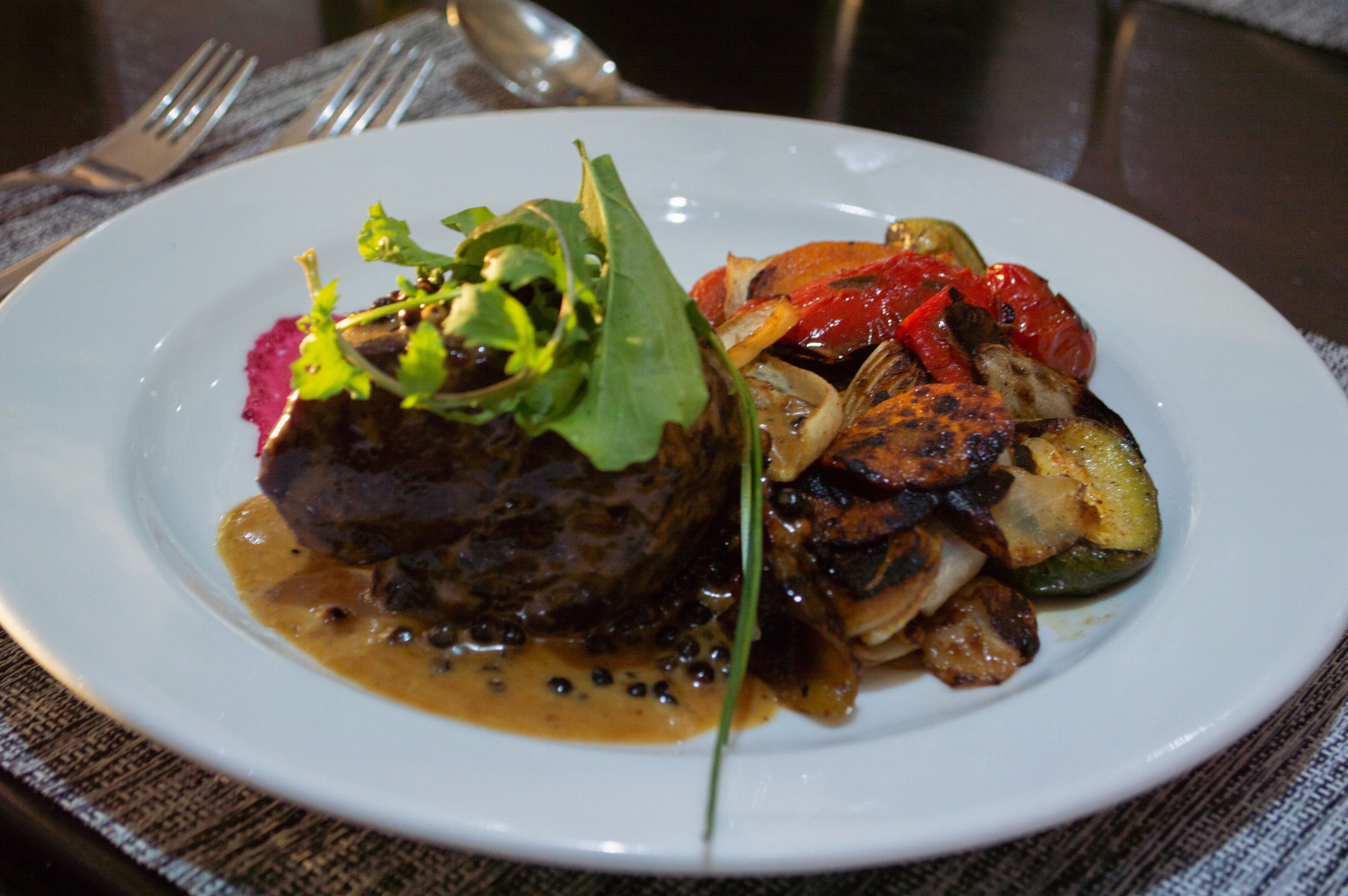 Ein Teller mit einem Steak, Gemüse und Soße.