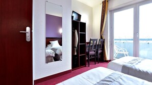 A hotel room with a bed, a desk, a chair, a wardrobe, and a large window. - Au Lion d'Or (Burnhaupt-le-Haut)