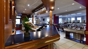 A spacious restaurant with a bar area, multiple dining tables, and a kitchen in the background. - Au Lion d'Or (Burnhaupt-le-Haut)