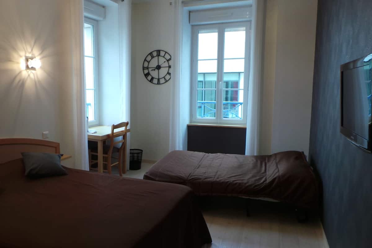 A bedroom with two beds, a desk, and a wall clock.