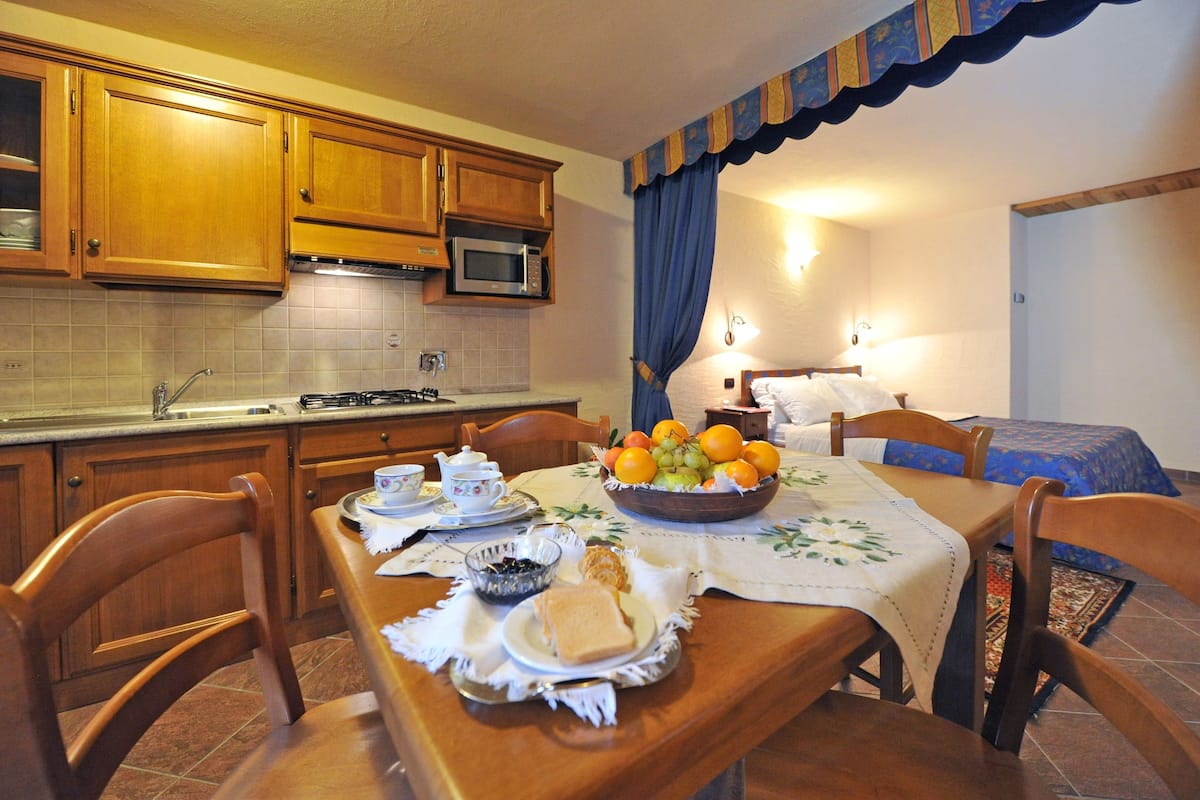 A compact kitchen with wooden cabinets, a microwave, and a dining area with a table set for breakfast.