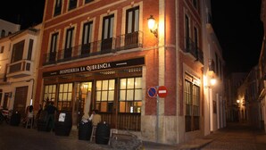 Un edificio con un cartel que dice "HOSPEDERIA LA QUERENCIA" de noche.