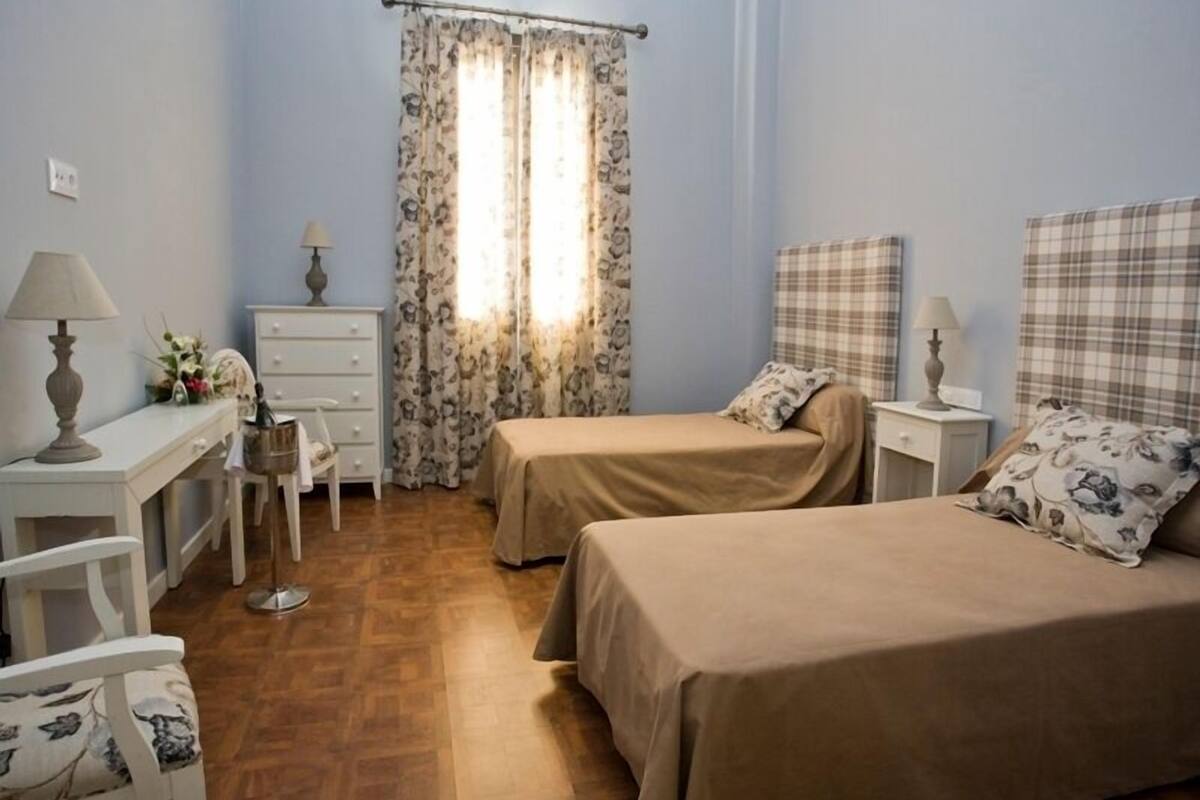 A bedroom with two beds, a desk, and a chair.