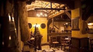 Un interior rústico con vigas de madera, una escalera y un comedor con mesas y sillas.