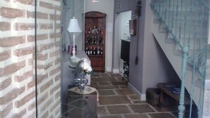 Una escalera con barandilla azul, un muro de ladrillo y una puerta de madera con un estante lleno de botellas.