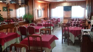 A restaurant with multiple tables and chairs, arranged in rows. - Hostal Sancho Garcia (Espinosa de los Monteros)