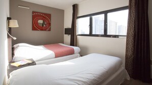 A hotel room with two beds, a window with curtains, a wall-mounted mirror, and a lamp. - Le Carmin (Vitry-sur-Seine)