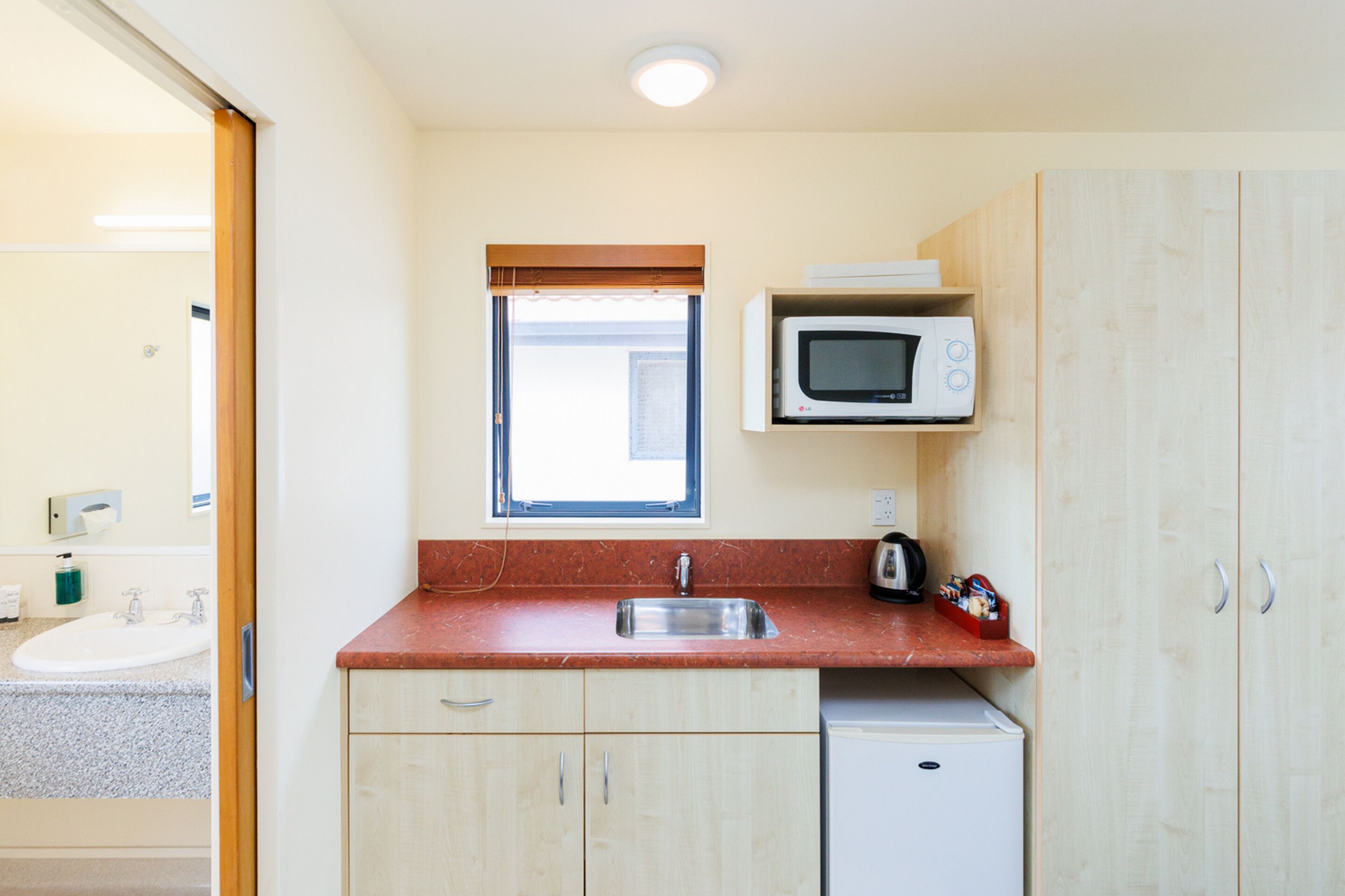 A compact kitchen with a sink, microwave, and a small refrigerator.