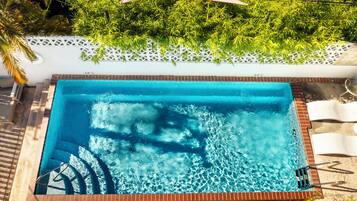 Alberca al aire libre, sombrillas en la alberca y camastros