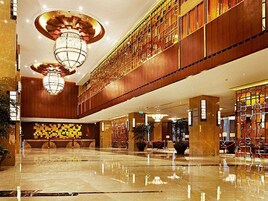 Un hall espacioso con techo alto, grandes candelabros y un suelo de mármol pulido.