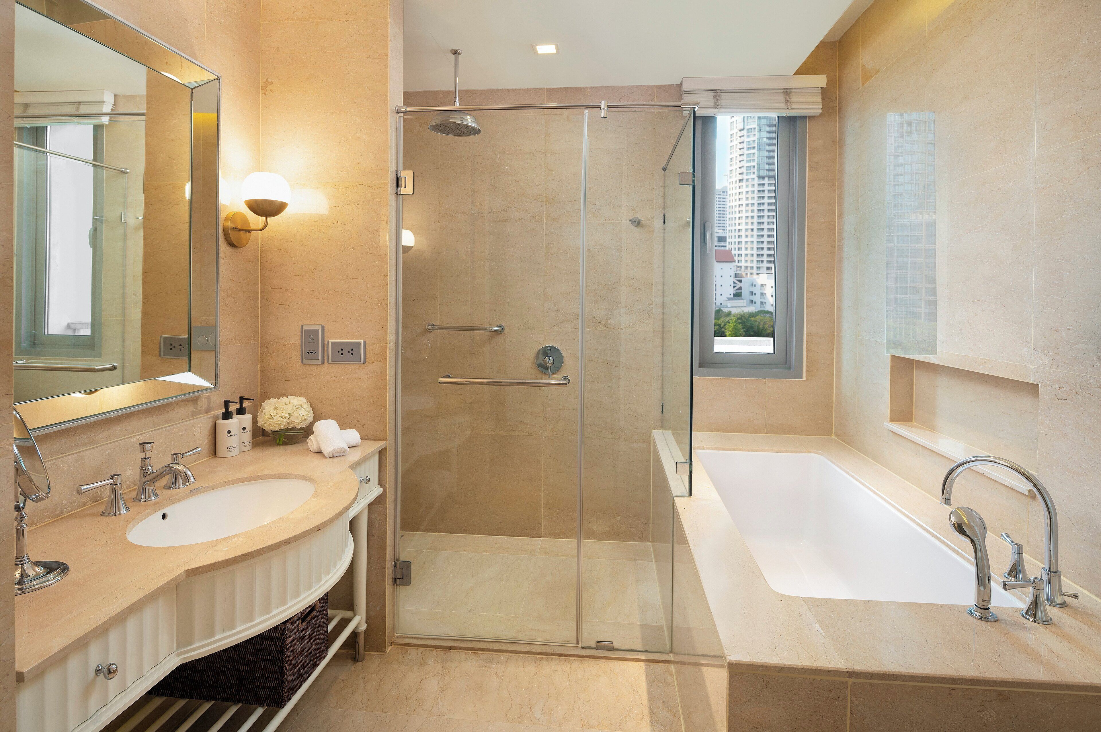 Un baño moderno con ducha envuelta en cristal, una bañera grande y un lavamanos con doble lavabo.