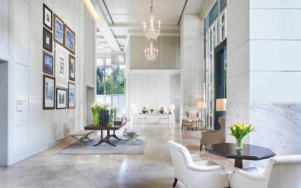 Een ruime lobby met een receptiebalie, een zithoek en kunstwerken aan de muur.
