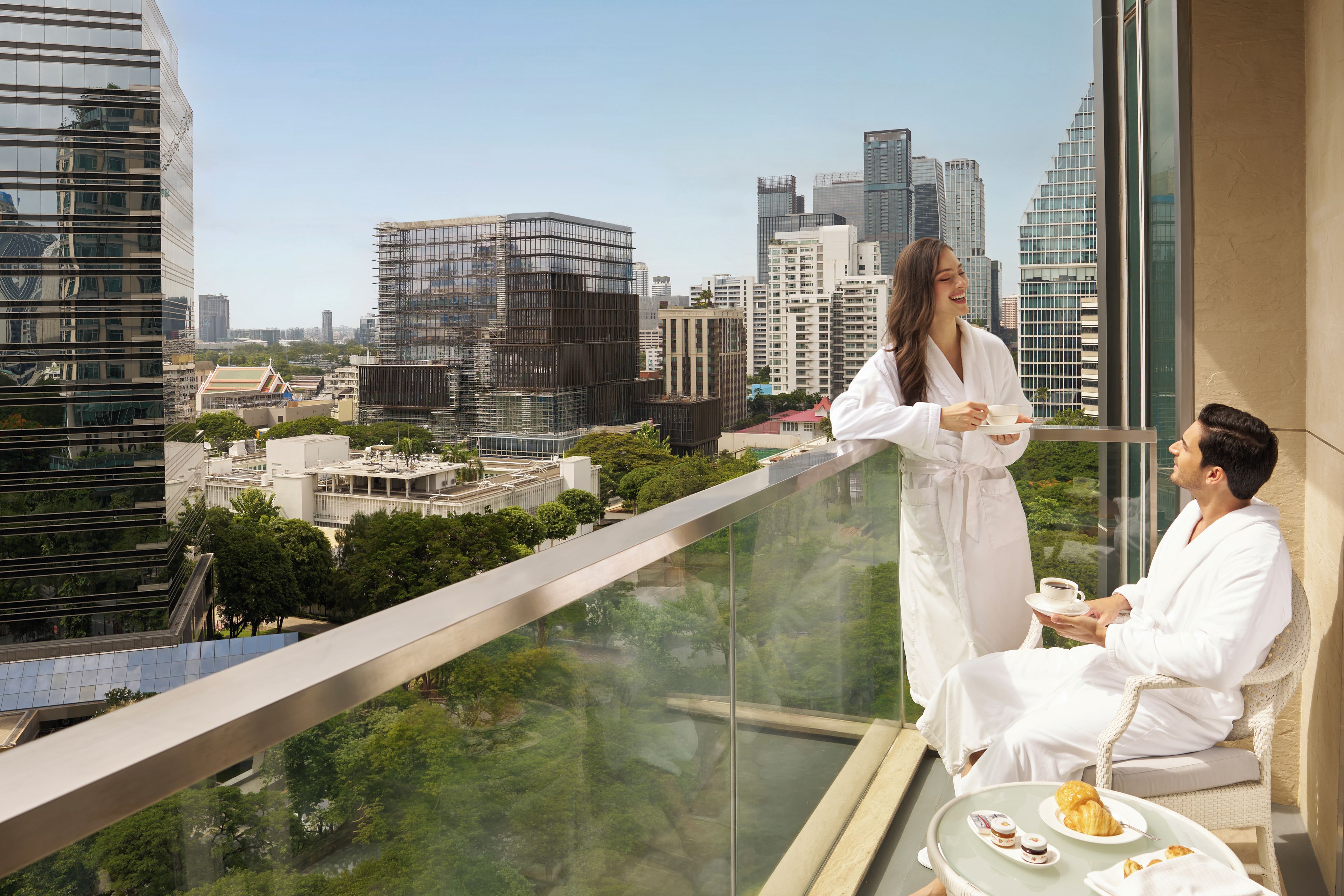 A high-rise building with a glass balcony overlooking a cityscape.