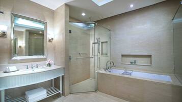 A modern bathroom with a glass-enclosed shower, a large bathtub, and a vanity with a mirror and sink.