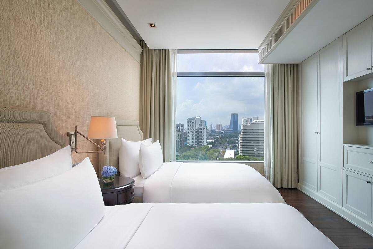 Una habitación de hotel con una cama grande, una mesita de noche, una lámpara y un televisor.