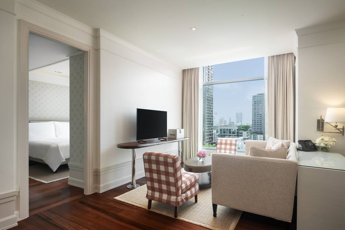 Habitación de hotel con cama, televisión, escritorio, silla, sofá y vista a la ciudad.