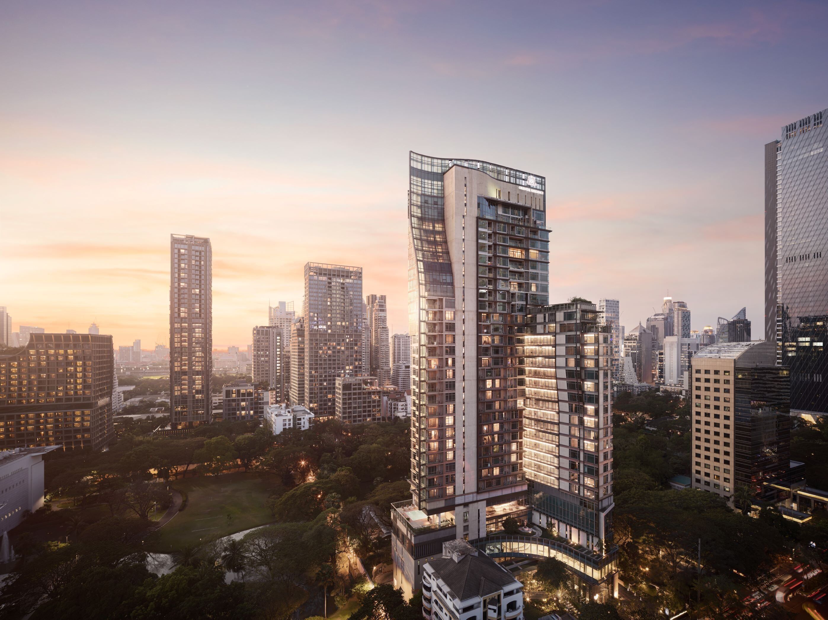 A high-rise building with a modern architectural design, surrounded by other tall buildings and a park area.