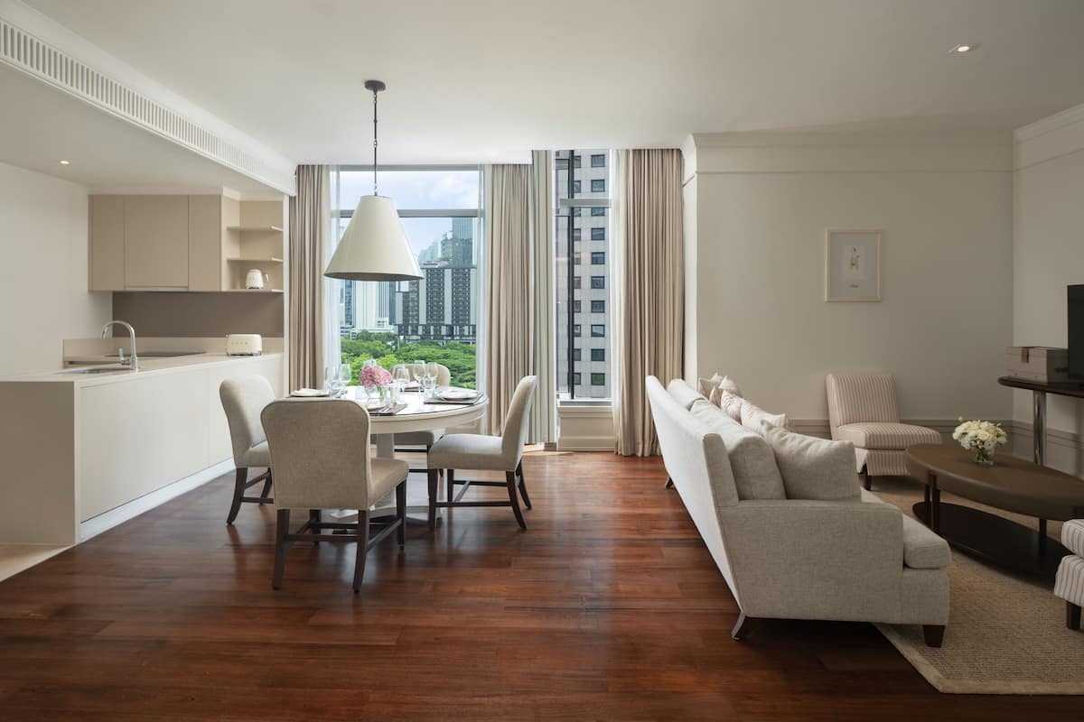 A modern living room with a dining area, a sofa set, and a view of a cityscape through large windows.