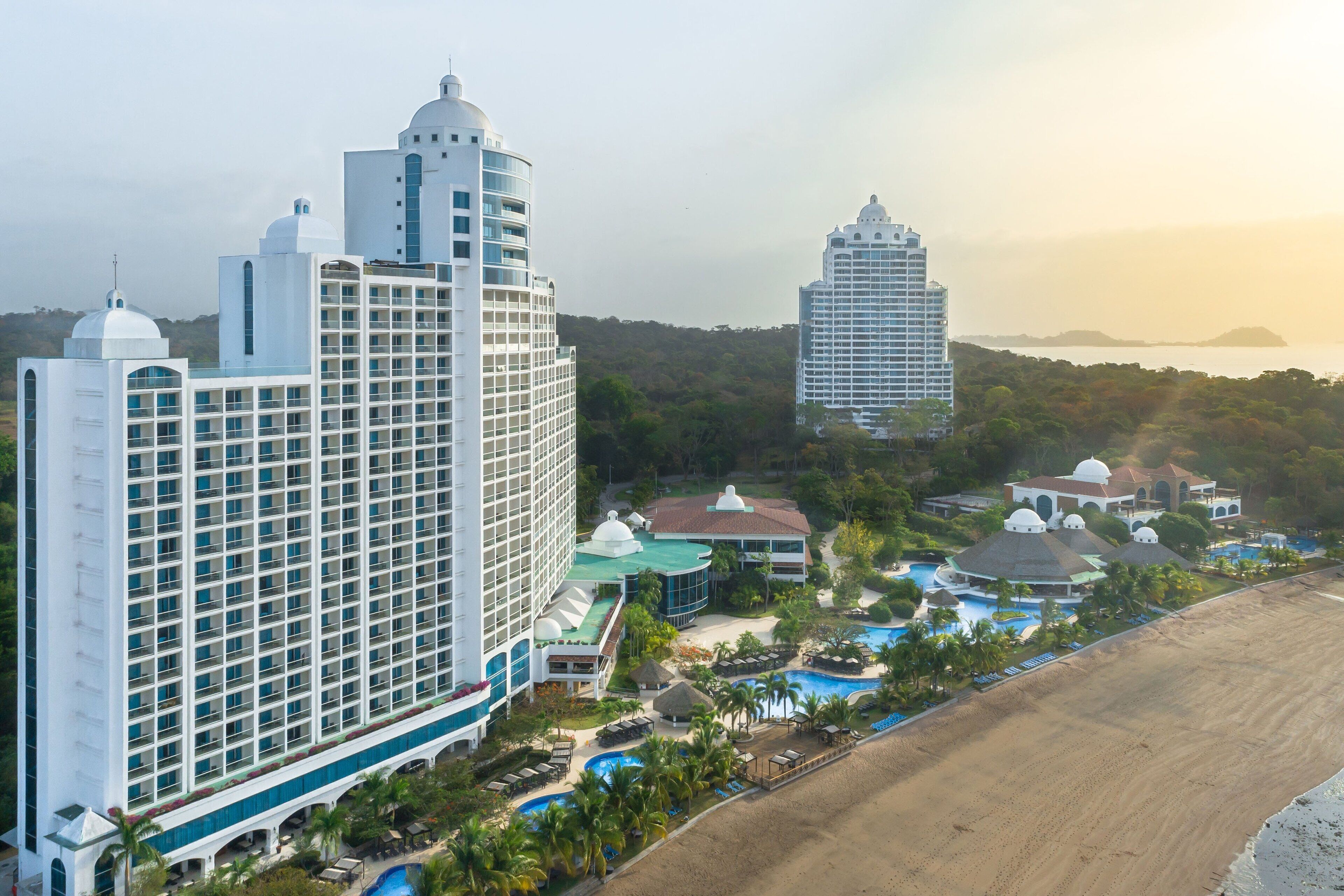 Un resort con varias edificaciones, una playa y una zona de piscina.