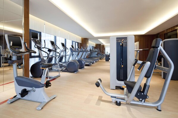 Un gimnasio moderno con cintas de correr, elípticas y estaciones de pesas.